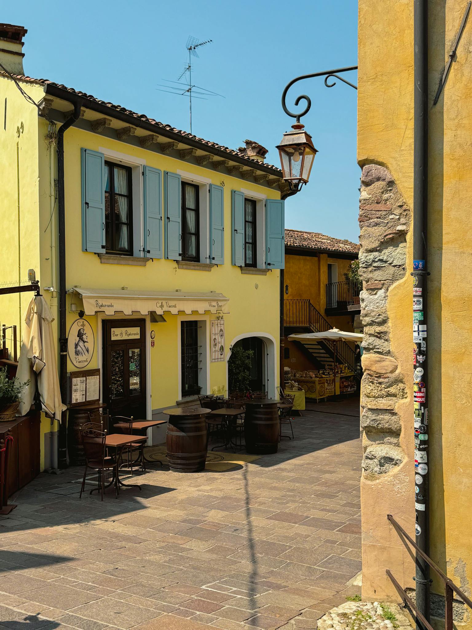 A picturesque café on a sunny day in a charming Italian town with vibrant yellow walls.