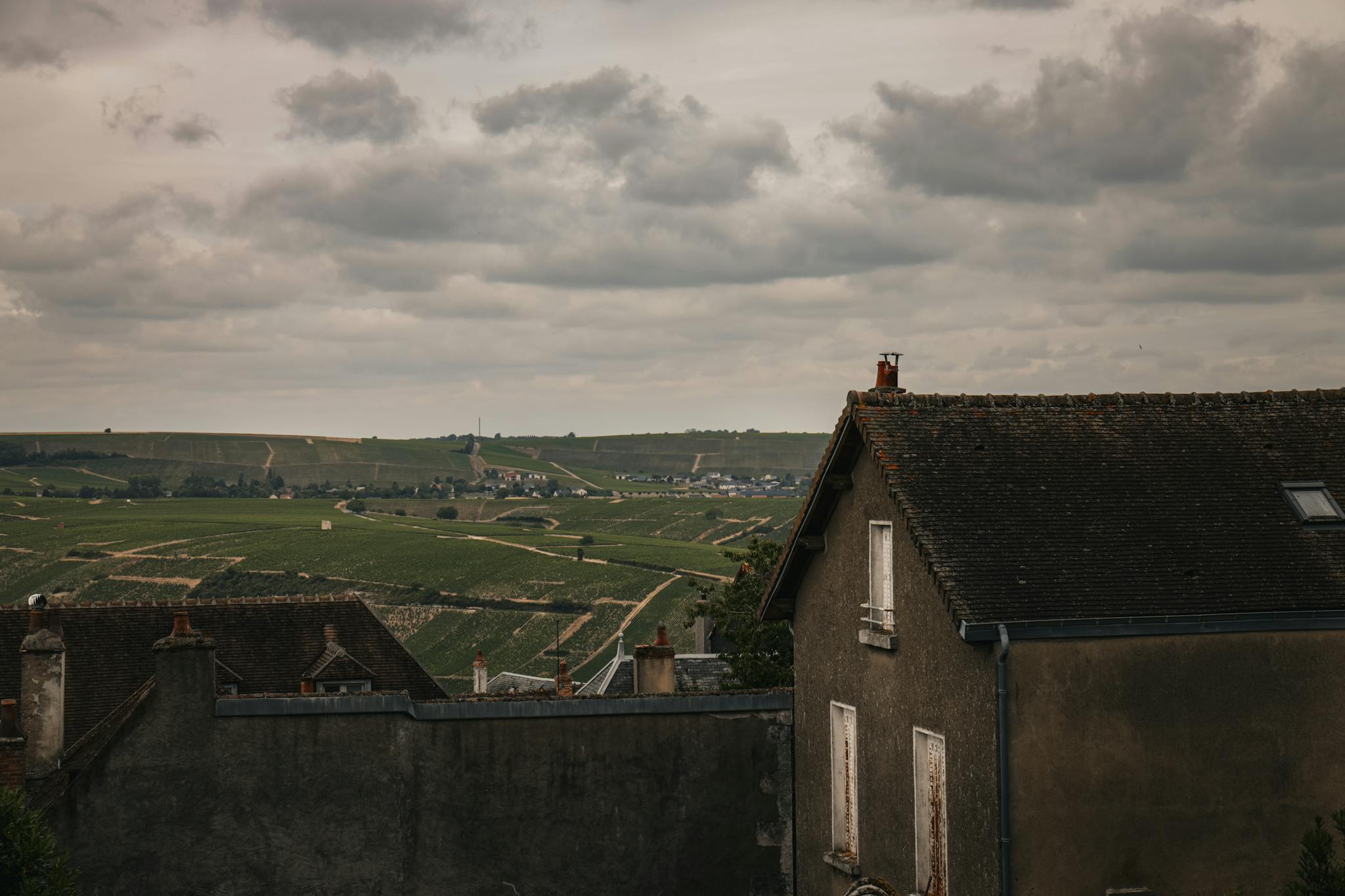 Beautiful view of Sancerre's countryside with vineyards and charming rooftops under a cloudy sky.
