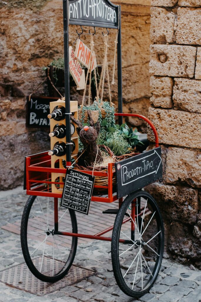 Charming Italian street food cart with wine, herbs, and local products on display.